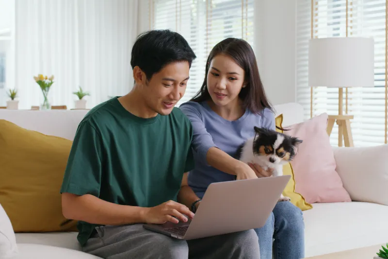 Couple sitting on couch looking at at laptop